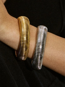 Macro detail of textured gold and silver chunky bangles with vertical ribbed patterns
