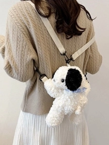 Cute black and white plush puppy backpack with beige straps on model's back