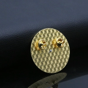 Macro shot of gold metal badge back with anti-slip texture and two butterfly clutches