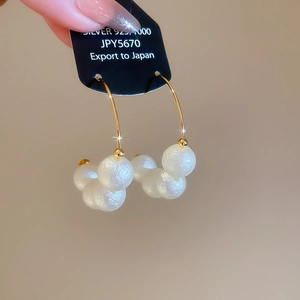 Detailed shot of 925 silver hoop earrings with white textured pearls on a gold finish