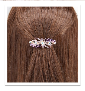 Détail de la pince à cheveux avec strass violets et bleus sur des cheveux bruns
