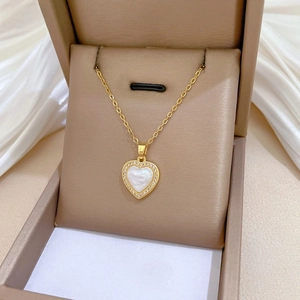 Detail of gold heart pendant with mother of pearl inlay and zirconia on silk