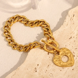 Détail du bracelet gourmette plaqué or 18 carats avec pendentif cœur gravé et fermoir à bascule