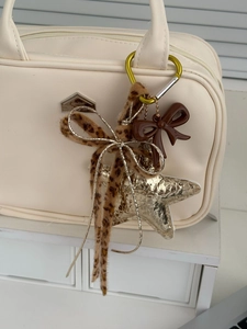 Detail of star bag charm with leopard print ribbon and golden sequins on a tote bag