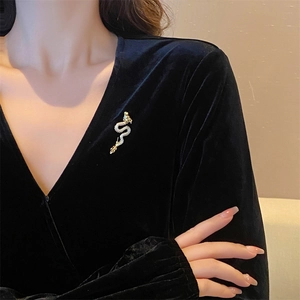 Exquisite golden dragon brooch with white zircons pinned on a black velvet dress