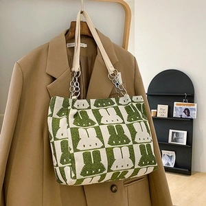 Knitted tote bag with green checkered bunny pattern and metal chain strap on a hanger
