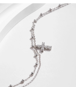Macro shot of double-layer S925 silver bracelet featuring cross pendant and tiny beads