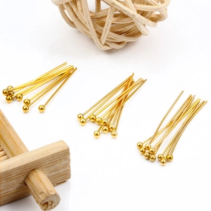 Spilli a testa tonda dorati per gioielleria fai da te su superficie di legno