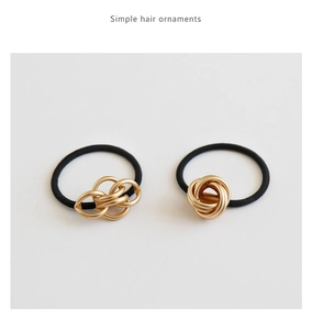 Close-up of black elastic hair ties with elegant golden metallic knot decorations