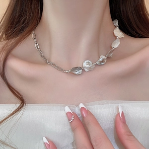 Primo piano di una collana a catena con conchiglia d'argento e perle indossata