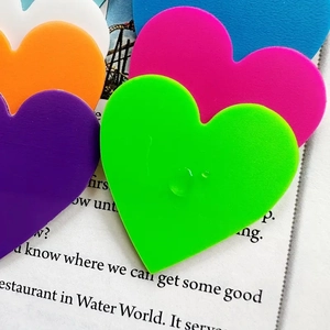 Macro shot of colorful acrylic heart charms in green, purple, and blue for DIY projects