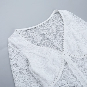 Détail du haut en dentelle blanche montrant le col en V avec des perles métalliques argentées