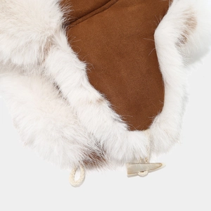 Detailed close-up of brown suede trapper hat with white faux fur lining and horn button