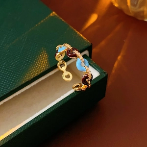 Dettaglio macro dell'anello smaltato con cerchi blu e rossi e zirconi su un cofanetto