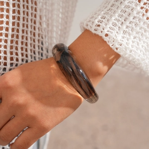 Close-up of wide tortoiseshell acrylic bangle with marble texture under natural sunlight
