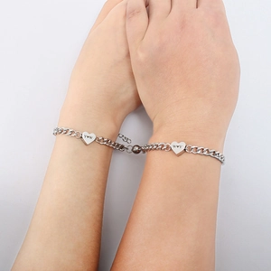 Close-up of magnetic heart pendants on silver Cuban chain bracelets for couples