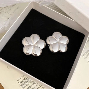 Detailed view of polished silver flower stud earrings in a velvet jewelry box