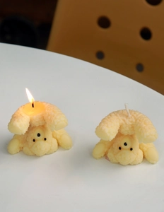 Detail of cute bear-shaped candle in cream yellow showing lit and unlit status contrast