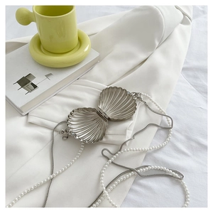 Detail of silver shell-shaped clutch bag with pearl chain strap and magnetic clasp