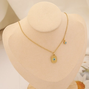 Gros plan du collier pendentif œil maléfique doré sur un support à bijoux beige