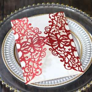 Detail of red glitter laser-cut floral wedding invitation card on a decorative plate