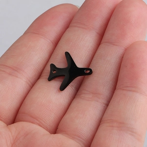Detail shot of a small black airplane pendant charm for DIY jewelry being held in hand