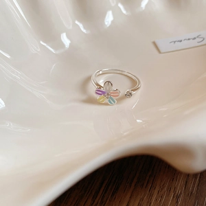 Vue macro d'une bague ouverte argentée avec pétales de fleurs colorés et pierre en zircon