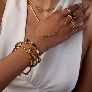 Detail view of bohemian gold bracelets and ring set featuring emerald green zircon stones