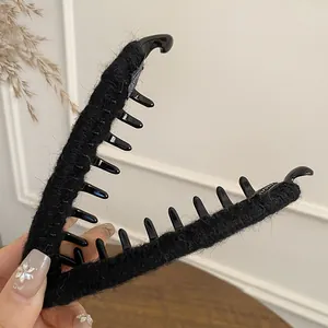 Detail of a large black flocked hair claw clip with plush texture and non-slip teeth