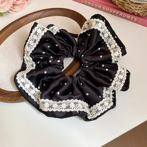 Détail du chouchou en satin à pois noirs avec bordure en dentelle blanche et froufrous