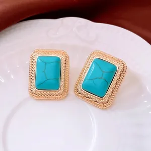 Vintage gold textured rectangle earrings with turquoise stone insets on white porcelain