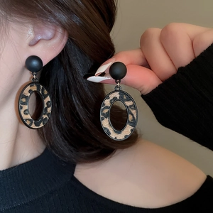 Gros plan de boucles d'oreilles ovales léopard avec clou noir mat sur le modèle