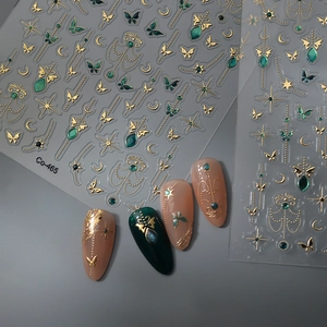 Close-up of gold butterfly and star nail stickers with emerald green accents Co-465