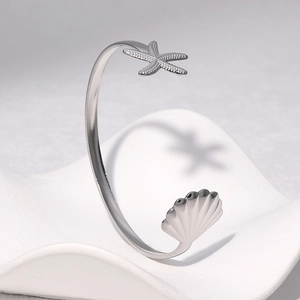 Silver stainless steel open bangle featuring a polished starfish and seashell design