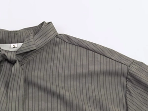 Detail view of striped blouse neckline with drawstring and size S label on grey fabric