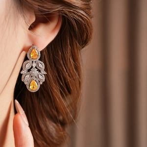 Detail of luxury drop-shaped flower earrings with yellow zircon gemstones on a model