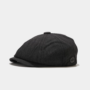 Detail of dark grey newsboy cap with textured twill fabric and round fashion patch