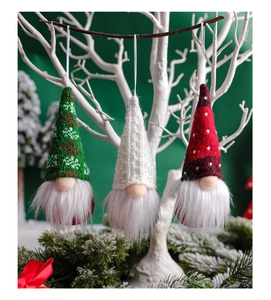 Three Christmas gnomes with knitted hats hanging on white branches for festive tree decor