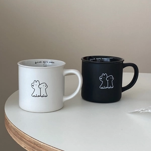 Detail of black and white ceramic mugs featuring cartoon patterns and inner text print