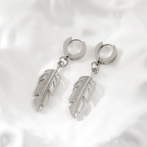 Polished silver titanium steel feather earrings in leaf design on a textured white background