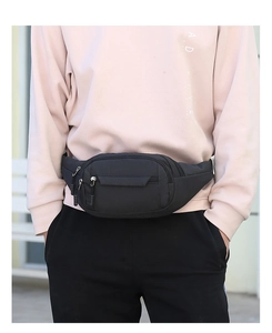 Close-up of black durable nylon waist bag worn on belt by male model in outdoor setting