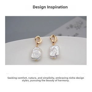 Detailed macro of baroque pearl earring with golden irregular square geometric metal hook