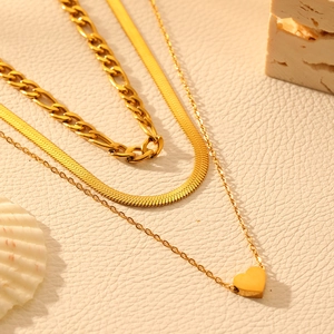 Three-layer 18k gold plated heart necklace with figaro and snake chains on marble