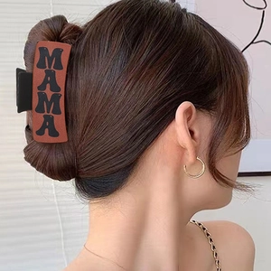 Brown Western style hair claw clip with black MAMA letter design worn by a female model