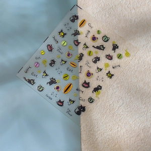 Detail of DIY black cat nail stickers featuring metallic fish bones and yarn ball designs