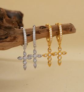 Macro shot of gold and silver S925 sterling silver cross earrings with pavé zircons
