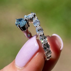 Macro shot of heart-shaped blue gemstone ring with oval side diamonds on silver band
