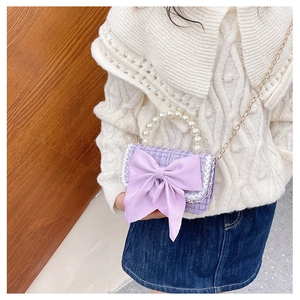 Detail of purple tweed girls' purse with a large bow, pearl handle, and golden chain strap
