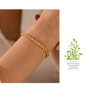 Detail of a gold twisted rope chain bracelet in stainless steel on a female wrist