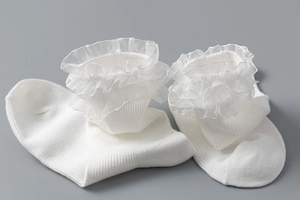 Détail de chaussettes en coton blanc côtelé avec dentelle en organza sur fond gris foncé